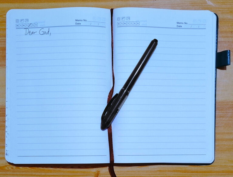Open journal with handwritten words “Dear God…” beside a pen, symbolizing gratitude journaling as worship to God.