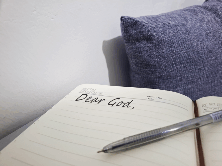 Opened Notebook with pen and a pillow besides it with a written text of "Dear God"