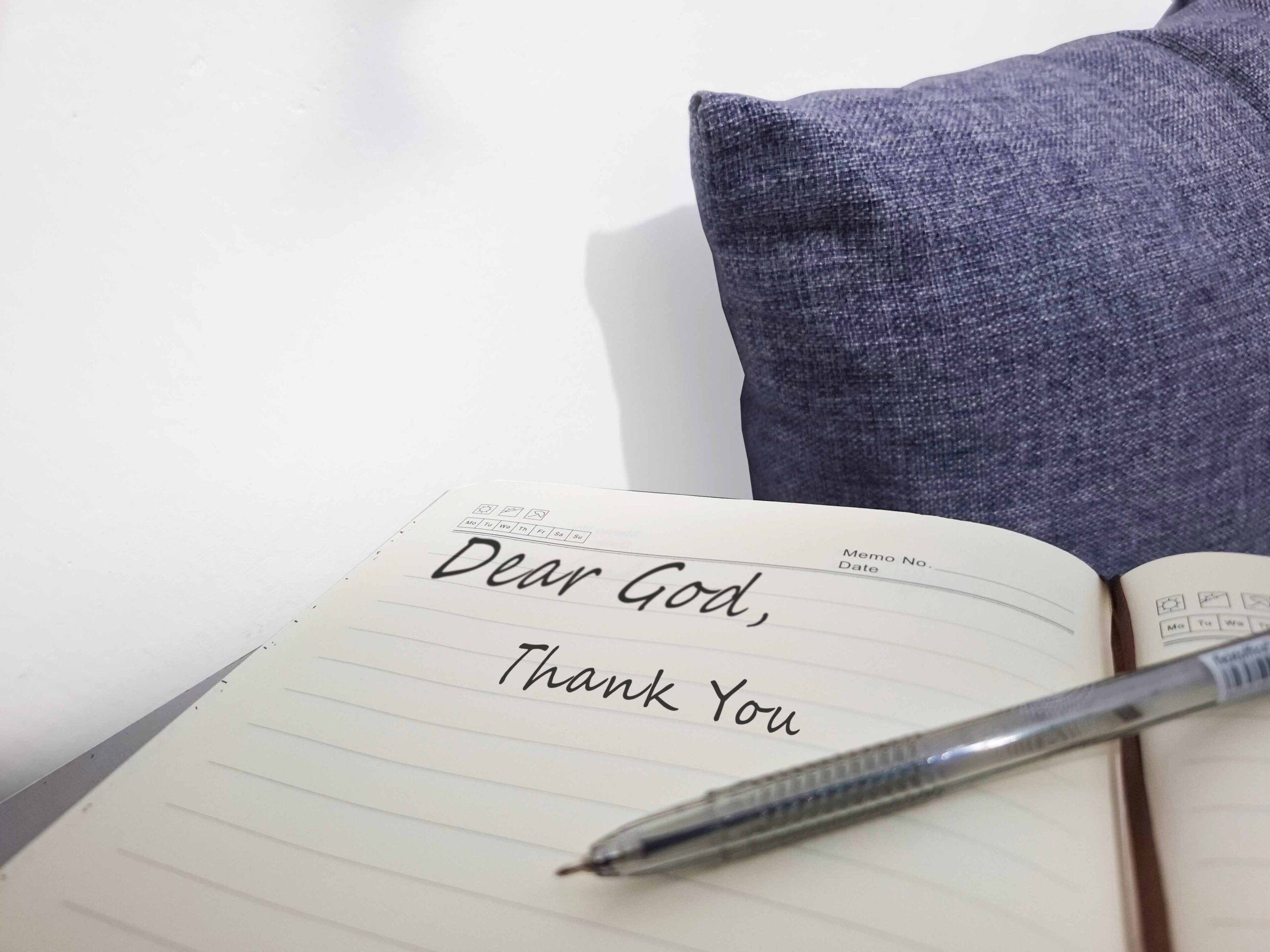 A woman journaling prayers of gratitude to God at a wooden desk, with soft sunlight symbolizing peace in the midst of life’s storms.